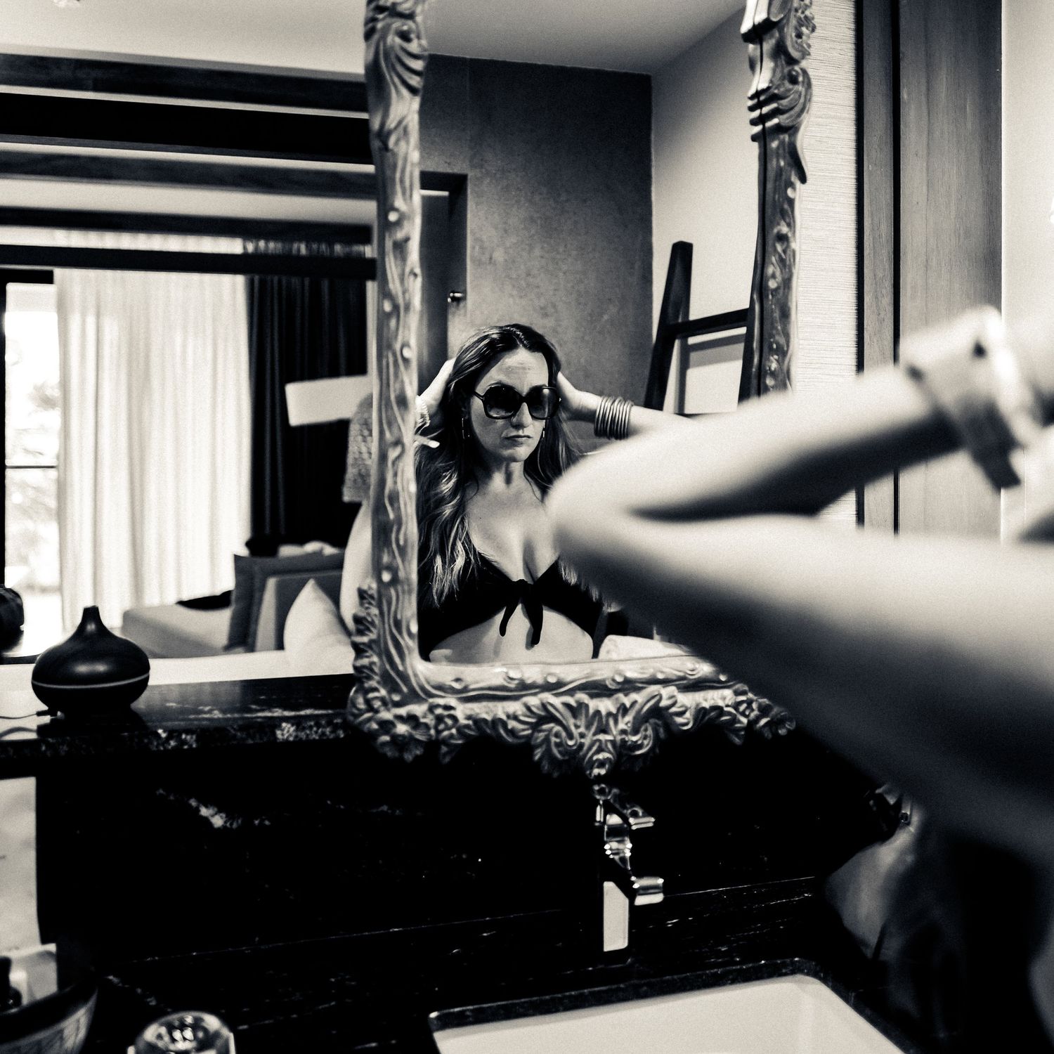 Artistic black and white mirror selfie showing a vintage mirror with ornate frame and reflective bikini pose.