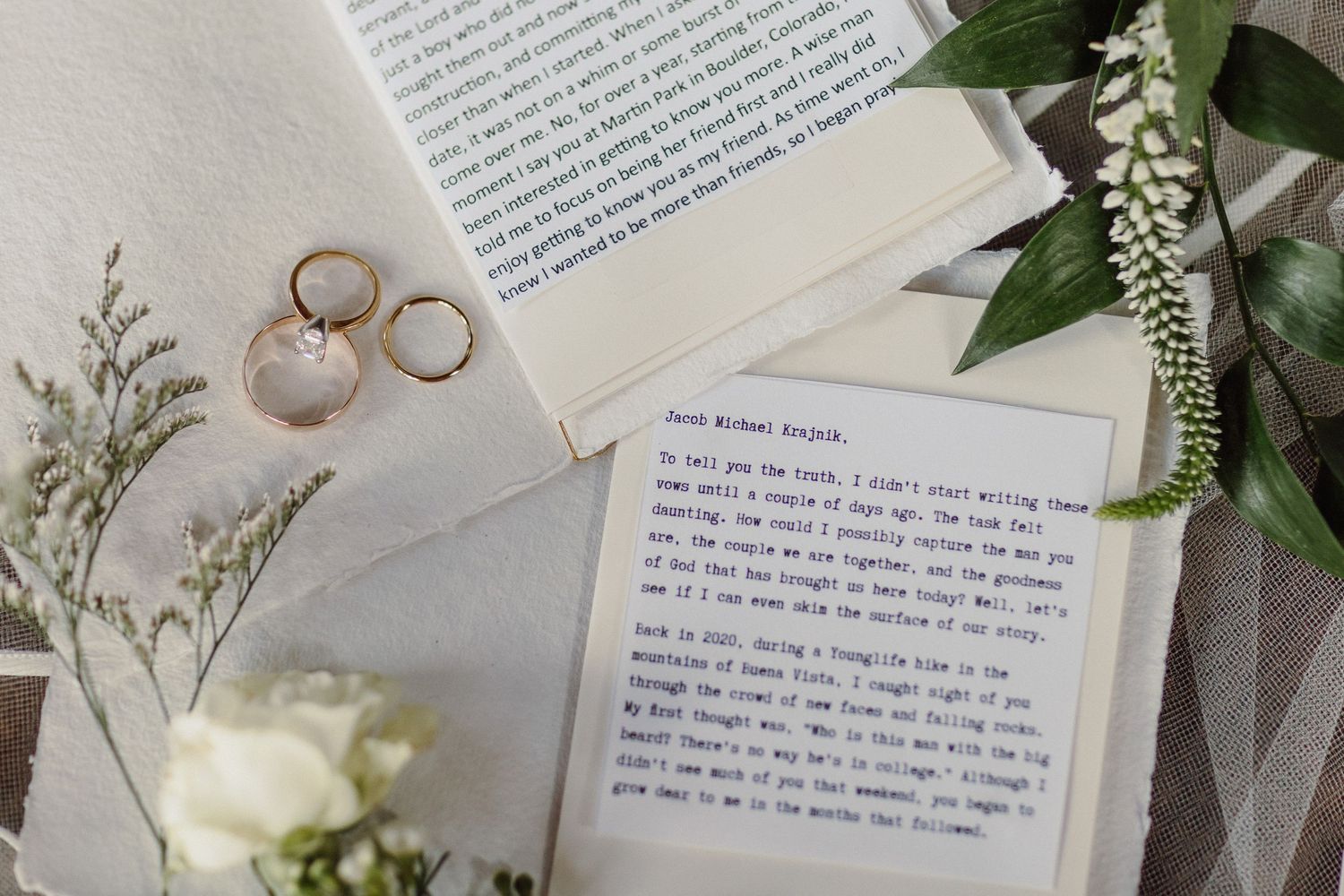 Wedding rings and floral details arranged with handwritten letters on paper.