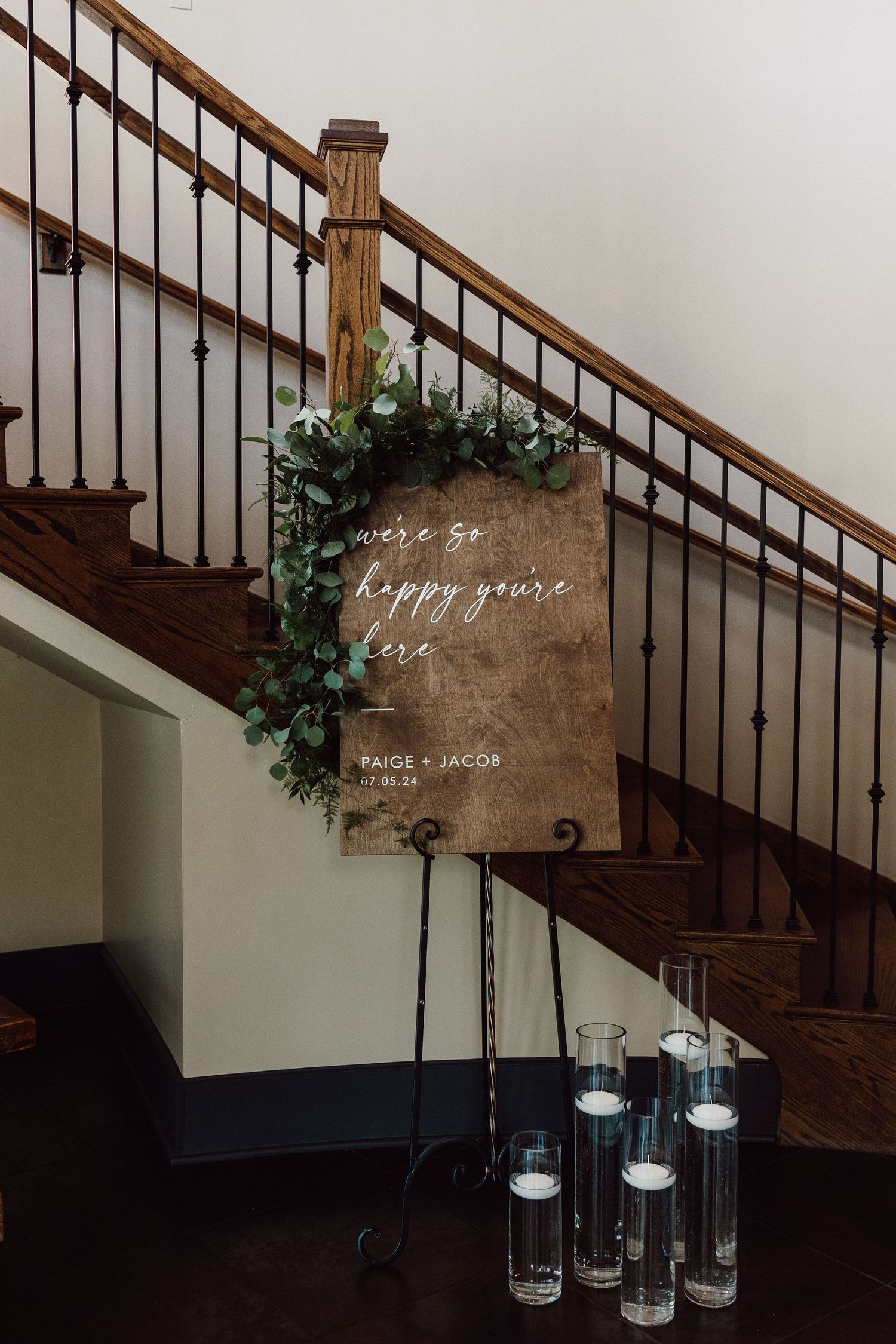 Wooden staircase decorated with greenery and candles featuring a rustic welcome sign.
