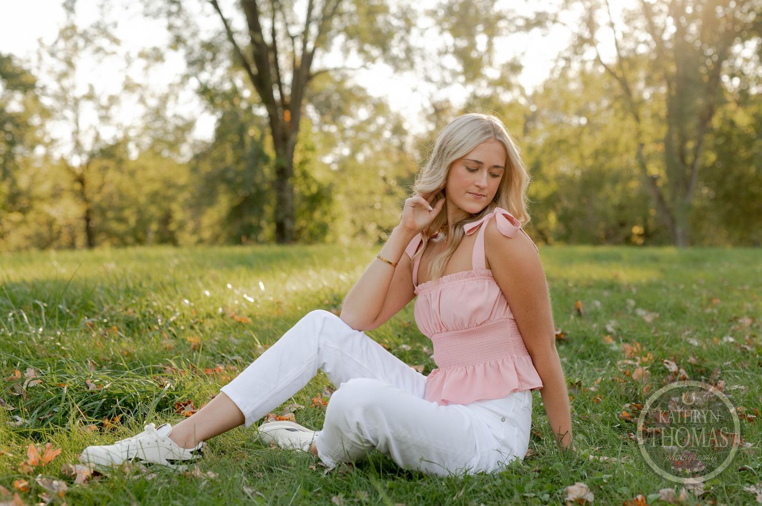 Relaxed outdoor portrait featuring pink top and white pants against natural backdrop.