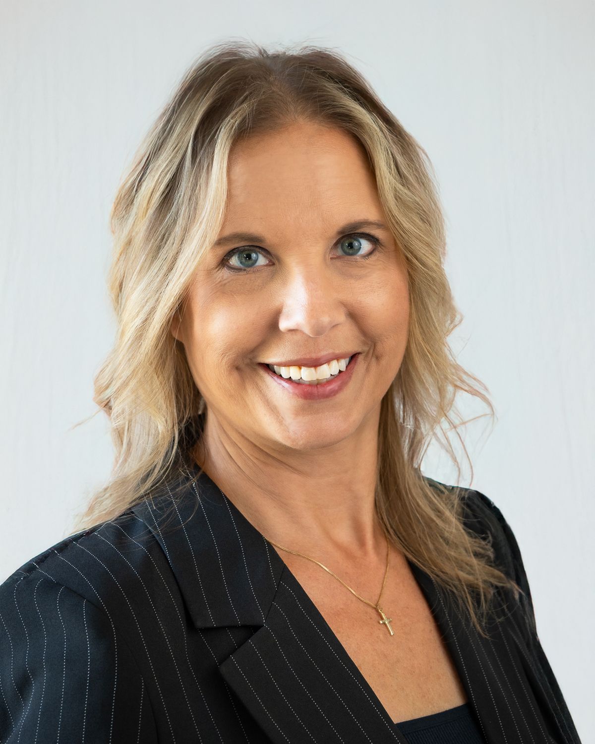 Professional headshots in pinstripe blazer against light background with engaging expressions.