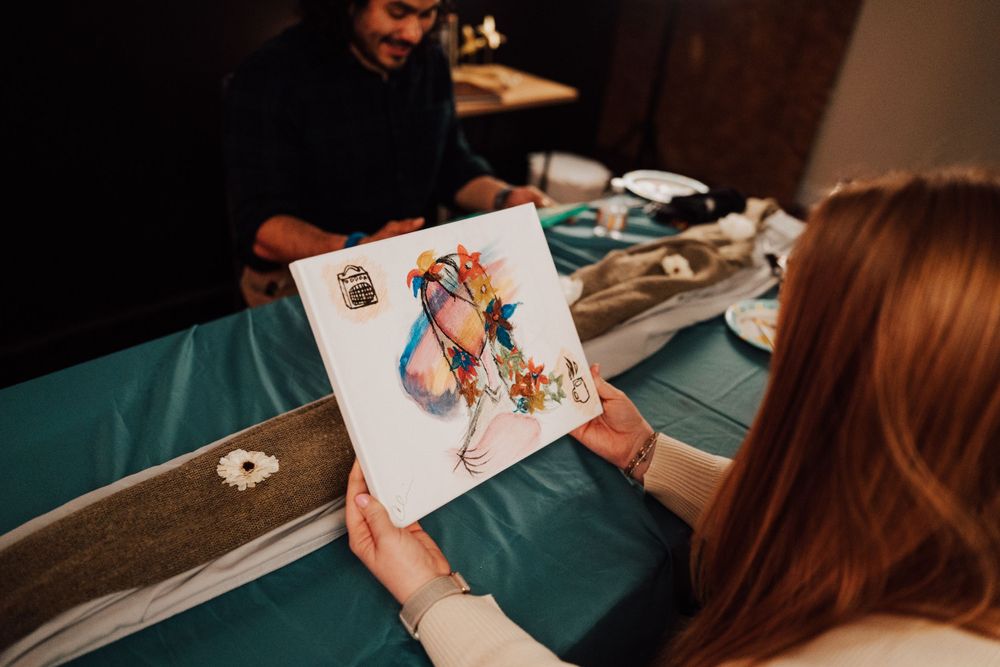 Someone holds up a colorful playing card while participating in a card game at a table with a green surface.