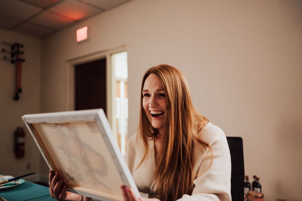 Future bride is happy about portrait her fiancé did of her at Sip & paint date night at Nicolle Aponte Photography studio in Middletown, PA