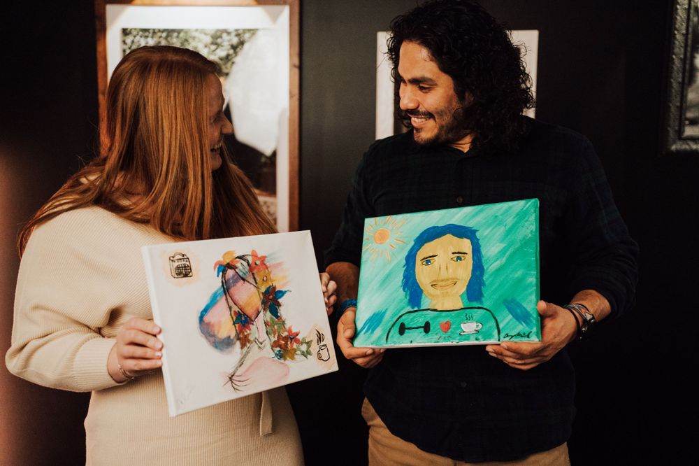 Engaged couple showcase their painted portraits at Sip & paint date night at Nicolle Aponte Photography in Middletown, PA