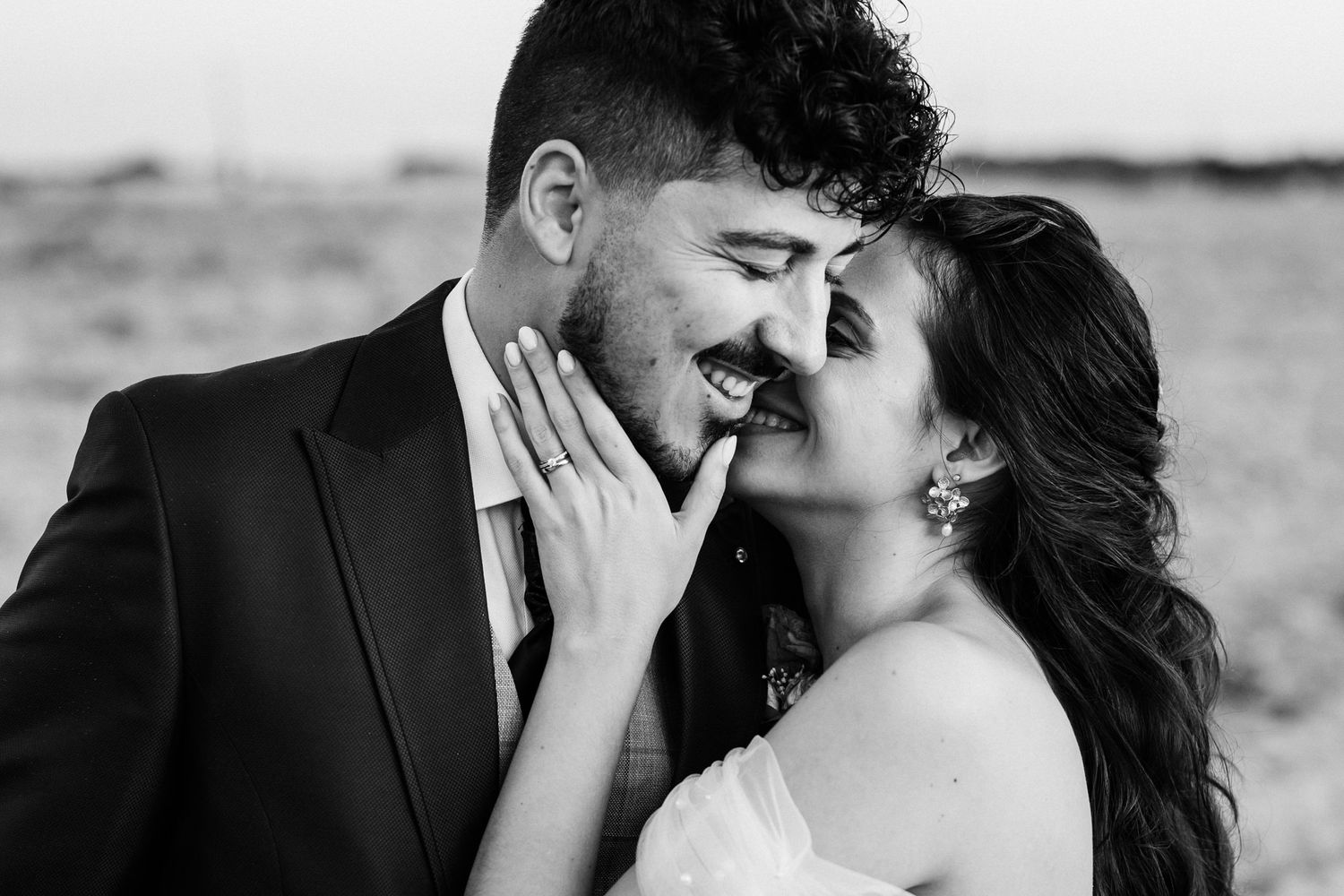 Sweet black and white wedding portrait of a loving couple sharing an intimate moment in a natural outdoor setting.
