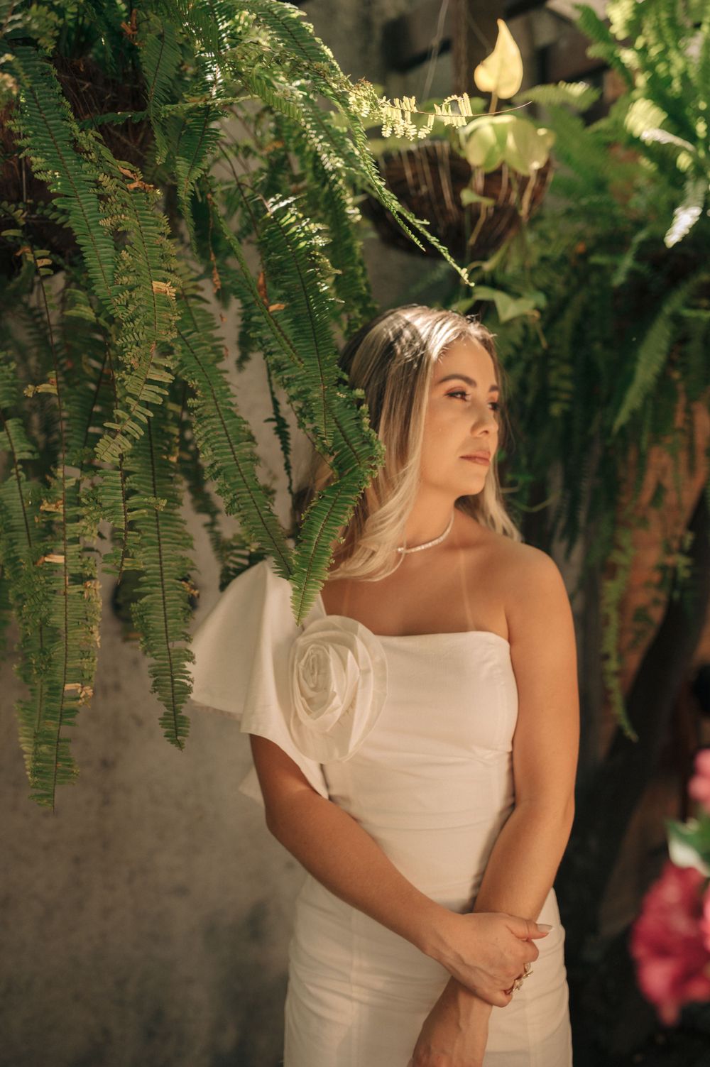 Elegant white dress portrait amidst lush ferns and greenery in natural lighting.