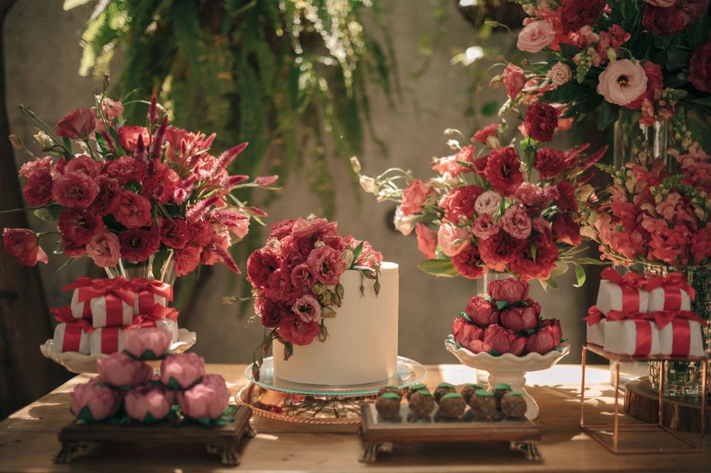Elegant floral arrangements with pink and red roses displayed on a table with decorative gifts.