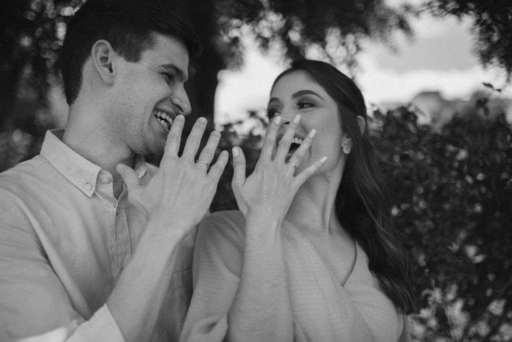 An intimate black and white portrait of a couple showing excitement with hands near their faces.