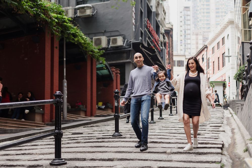 People walking up a sloped street with historic buildings in Hong Kong's Central district.