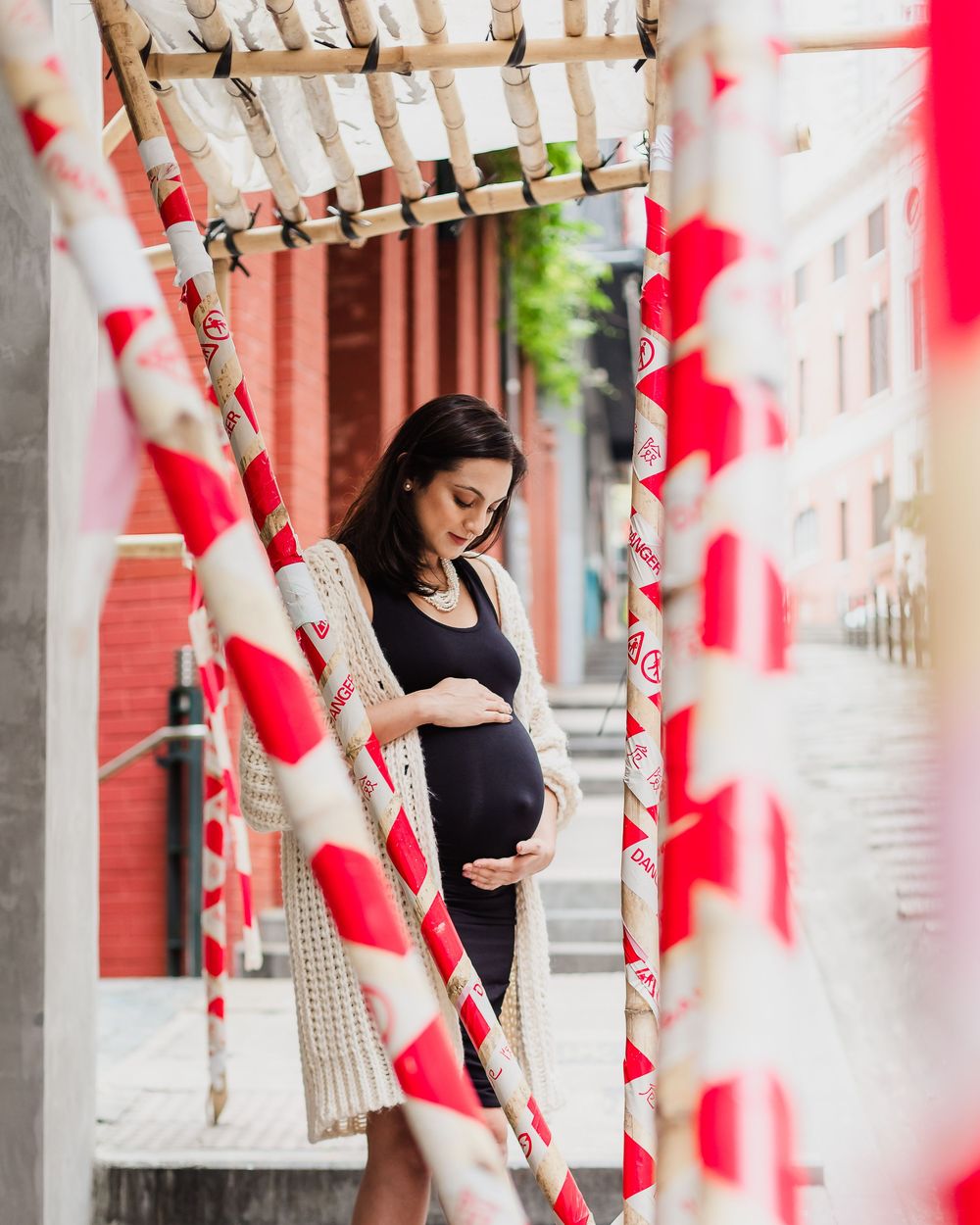 Maternity photo with red and white stripes framing an intimate outdoor moment in an urban setting.