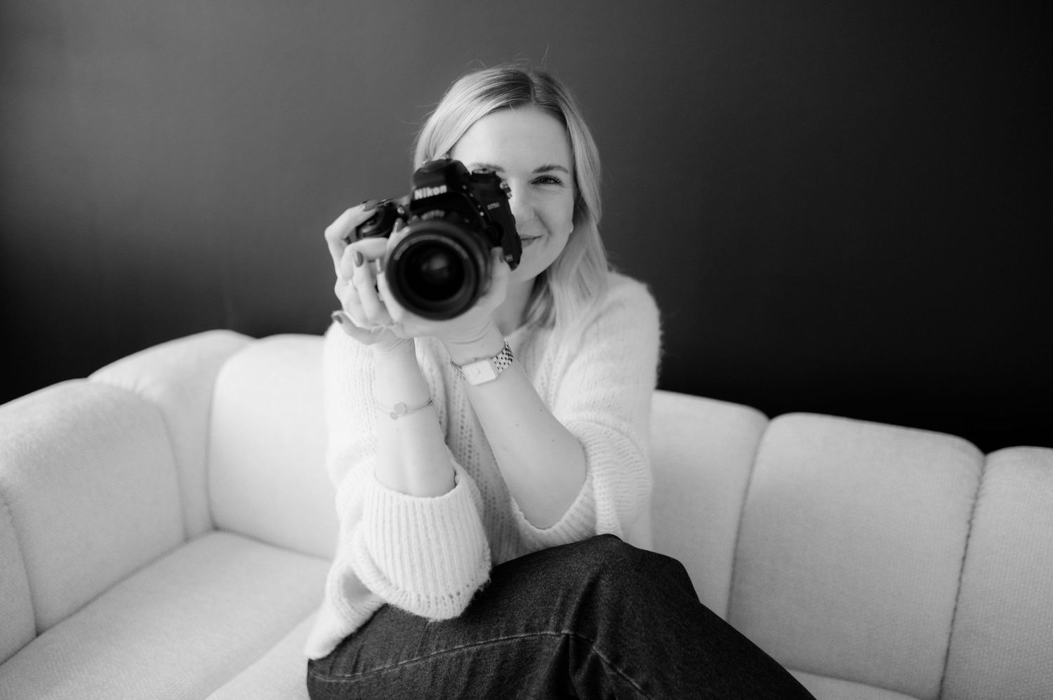 Photographer in striped shirt capturing moments in bright industrial studio space.