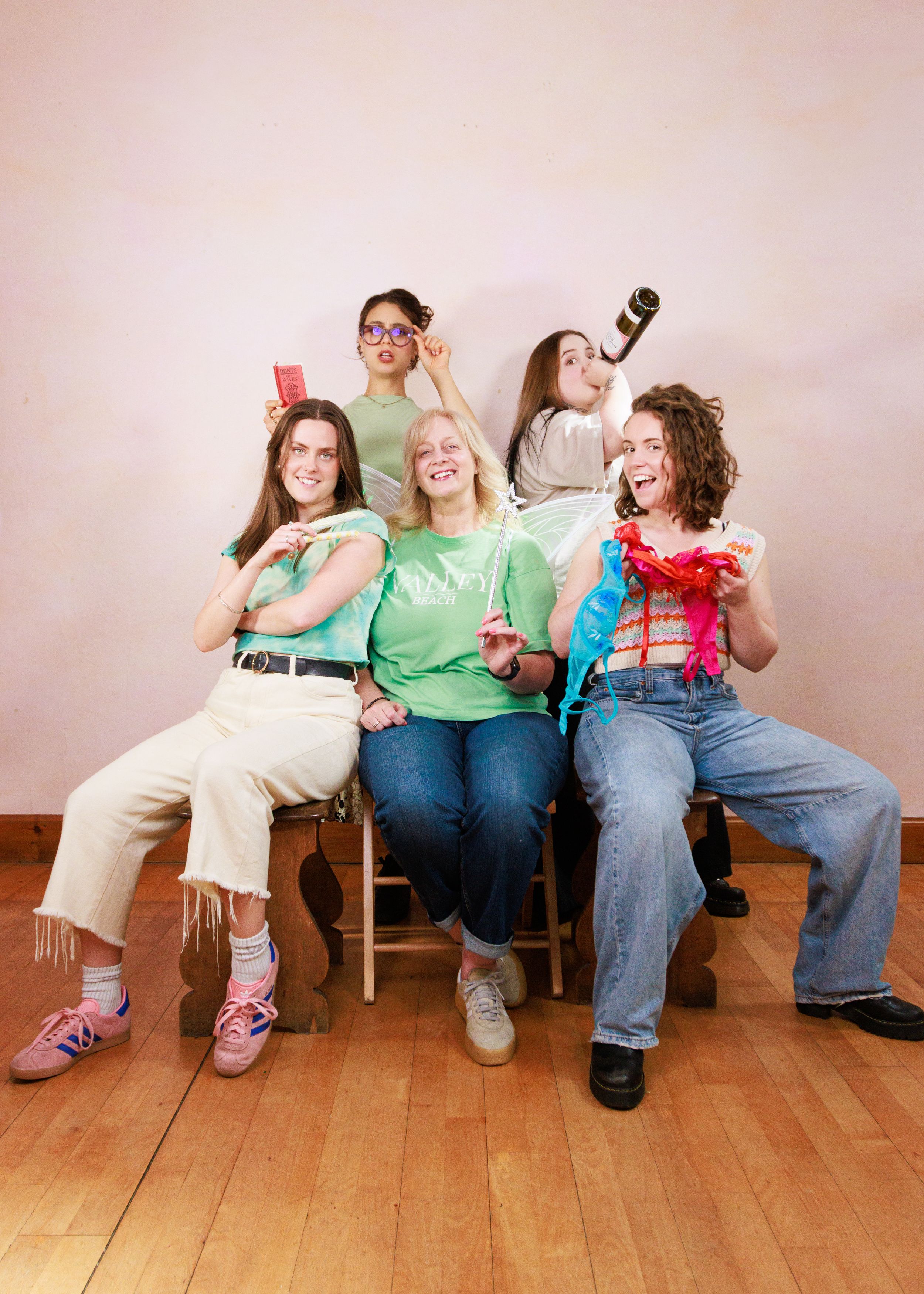 Group sitting casually together on wooden bench while using mobile phones with expressions of joy and laughter.