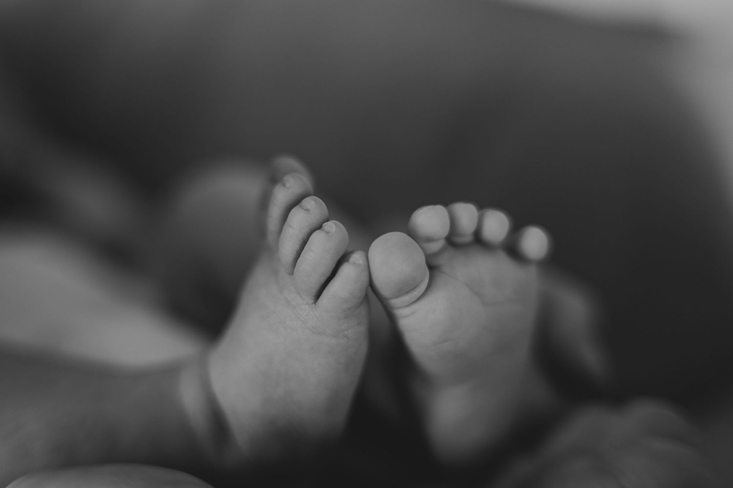 Black and white close-up of bare feet resting on soft bedding.