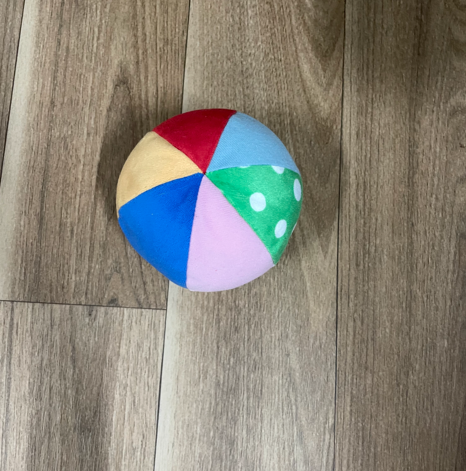 Colorful beach balls with polka dot patterns displayed on a gray wooden floor.