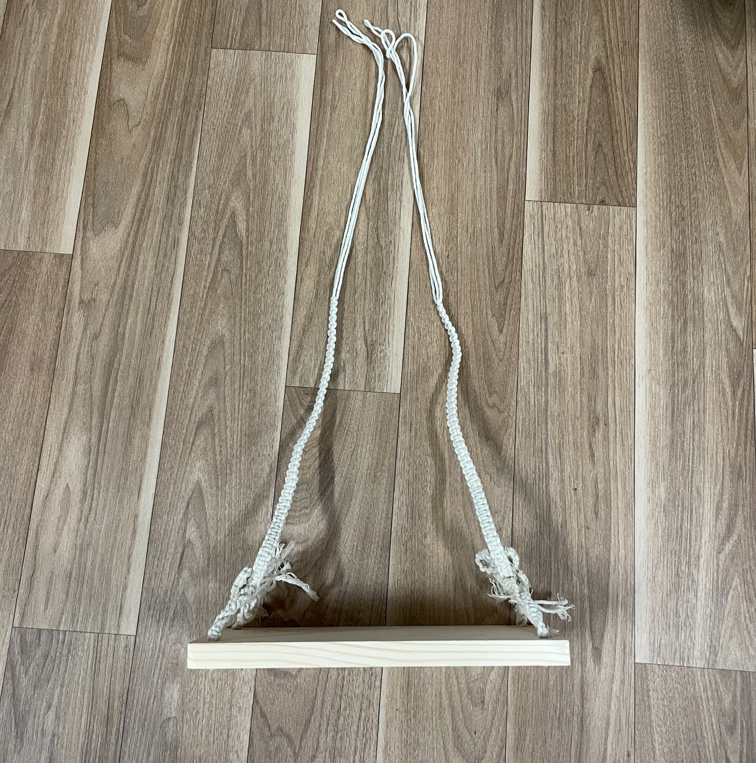 White rope arranged in a curved pattern against light wooden flooring.