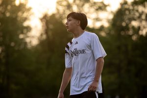 Soccer players practicing on field at golden hour with trees silhouetted in background.