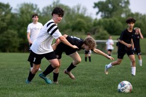 Players compete for possession of the soccer ball during an intense match on a grassy field.