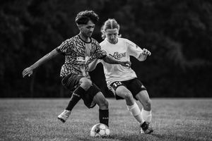 Soccer players battle for possession of the ball during an intense match on a grassy field.