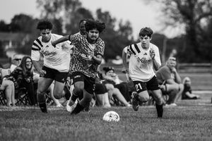 Soccer players rest and chat while laying on grass field during outdoor practice session.