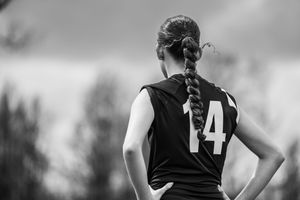 Black and white photo of sports player with number 14 jersey viewed from behind with braided hair.