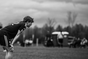 Black and white photo of soccer player in Adidas uniform catching their breath during outdoor match.