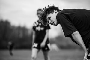 Black and white image sequence of a parkour athlete performing an aerial flip off a rectangular obstacle outdoors.