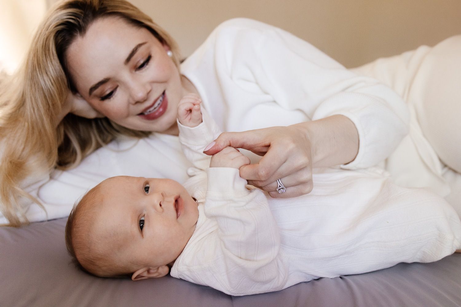 A mom holds her baby's hand during their newborn photoshoot in the Bay Area