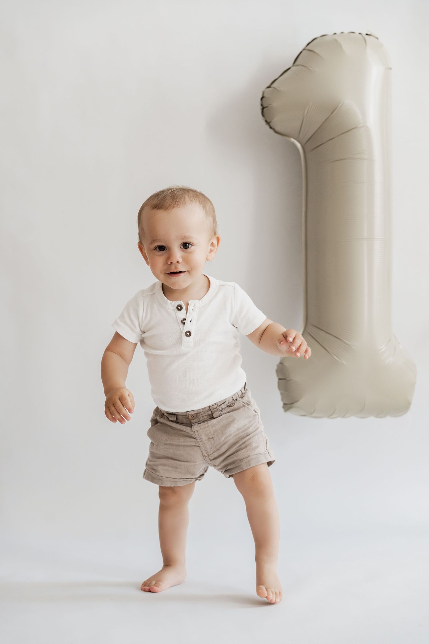 Kleiner Junge beim Geburtstagsfotoshooting im Fotoatelier Korneuburg, natürliches Geburtstagsfoto mit Luftballons und leuchtender Zahl 1