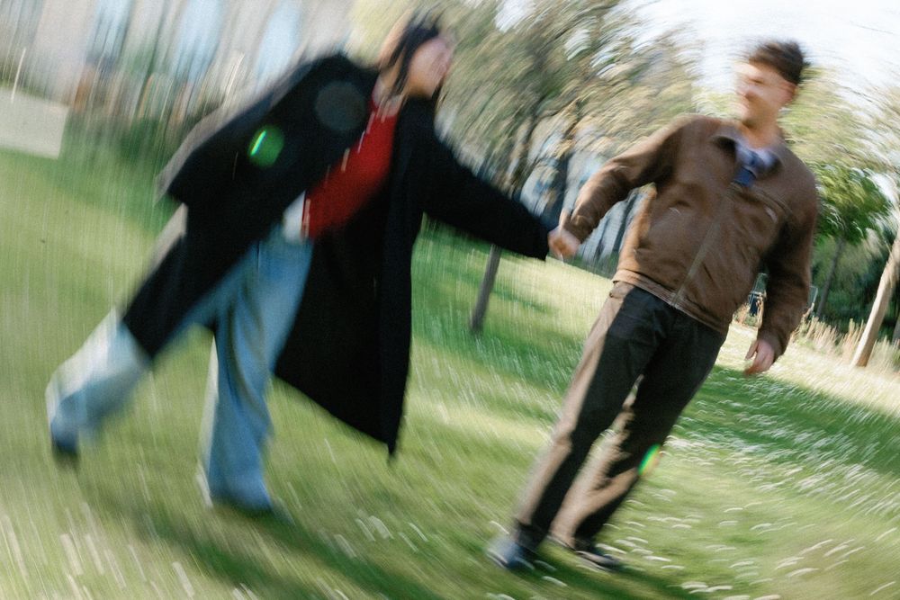 A person walking in a black coat appears as a blurred motion sequence showing movement from left to right against a green background.