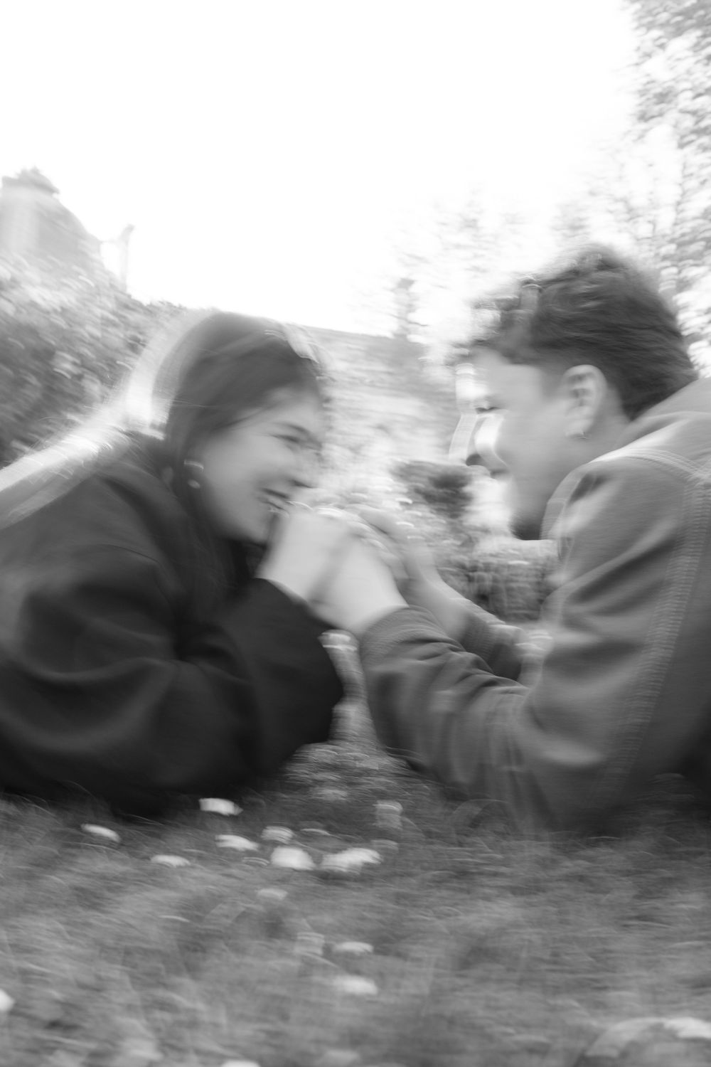 A black and white blurred photo of two people laughing together outdoors.