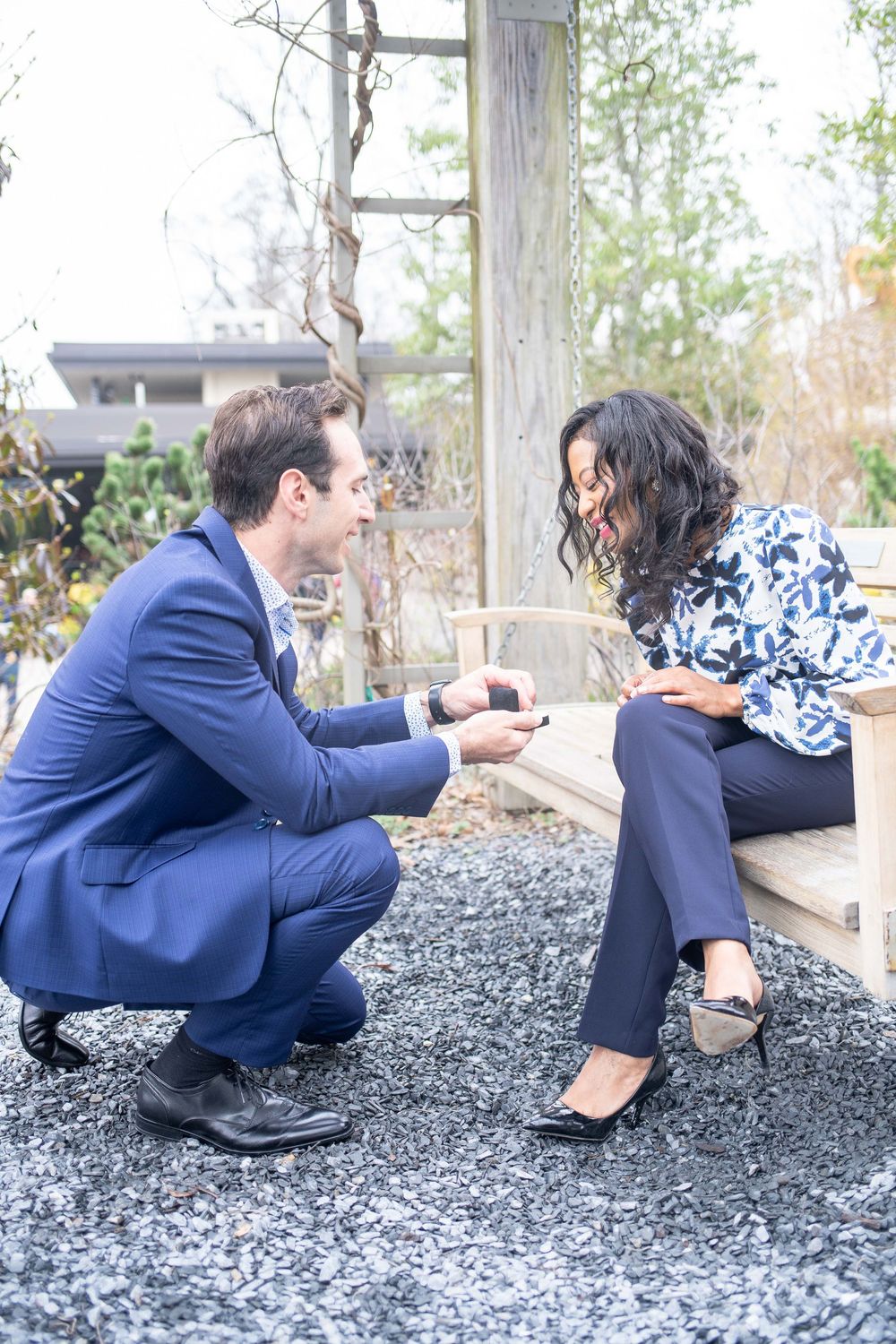 Romantic proposal scene with couple in business attire on outdoor bench.