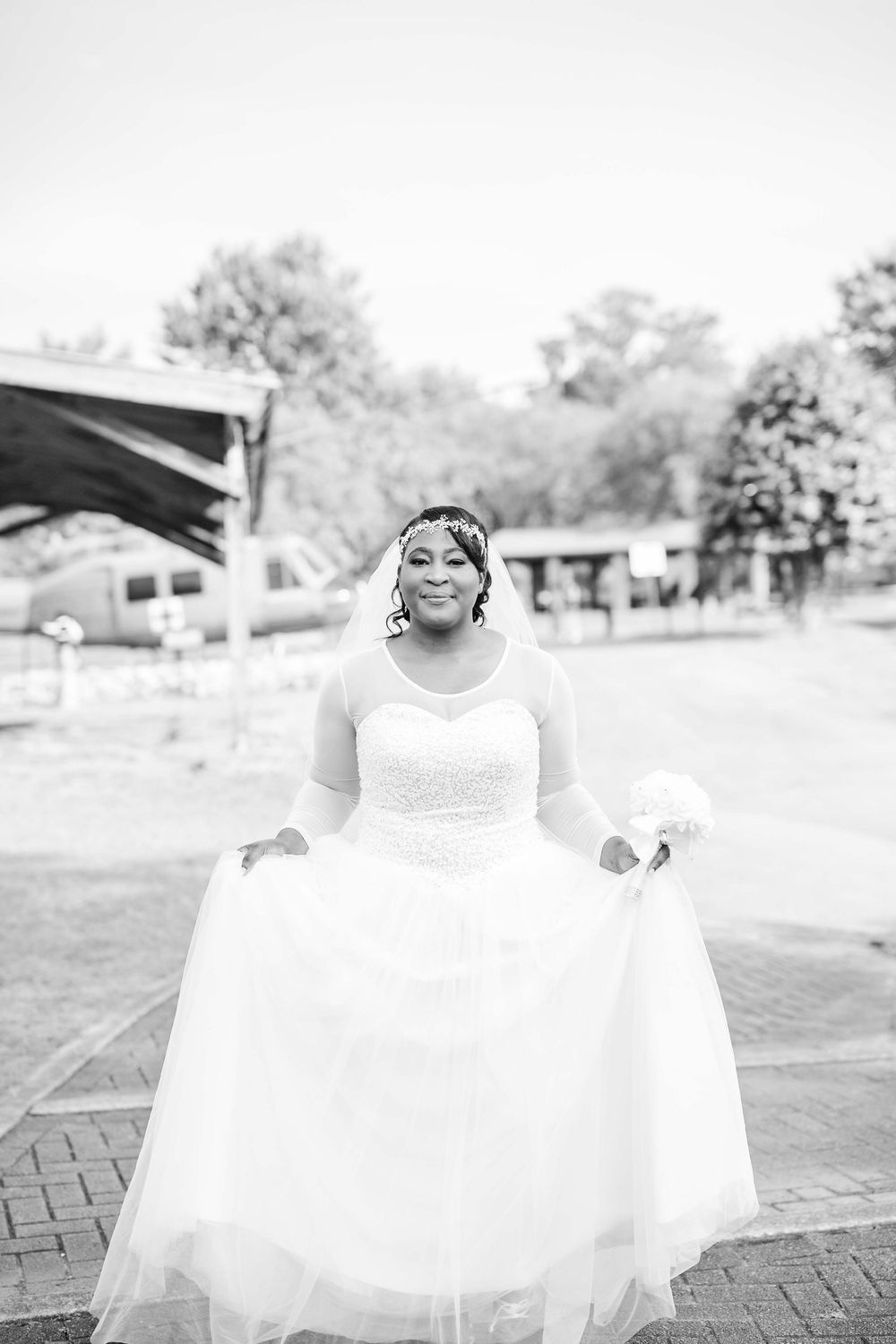 Black and white bridal portrait showcasing flowing tulle wedding gown on brick pathway.