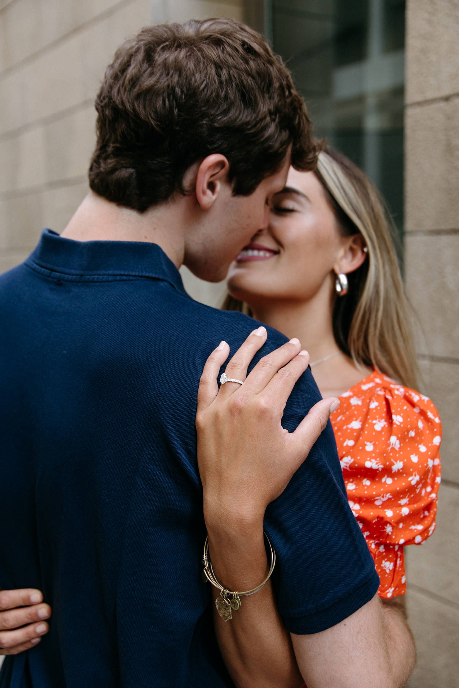 Intimate moments shared against brick wall backdrop in urban setting.