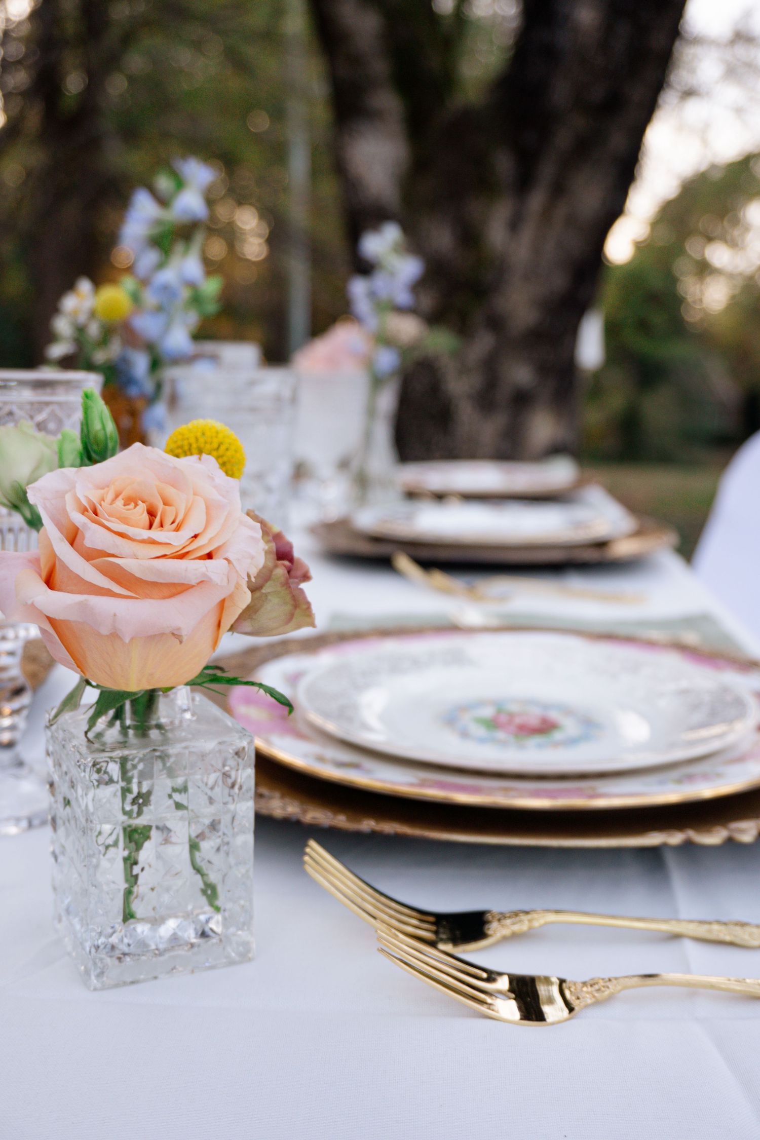 A romantic wedding moment captured beneath a floral arch near a rustic stone building with autumn-colored decor.