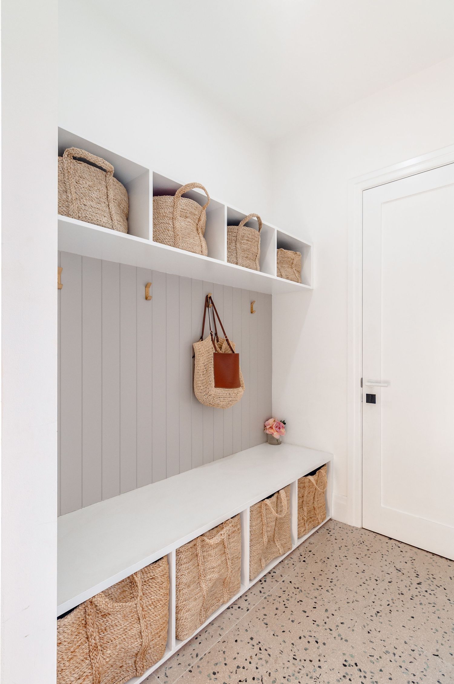 Sleek white mudroom with built-in storage benches and gray paneled walls showcases organized cubbies and hooks.