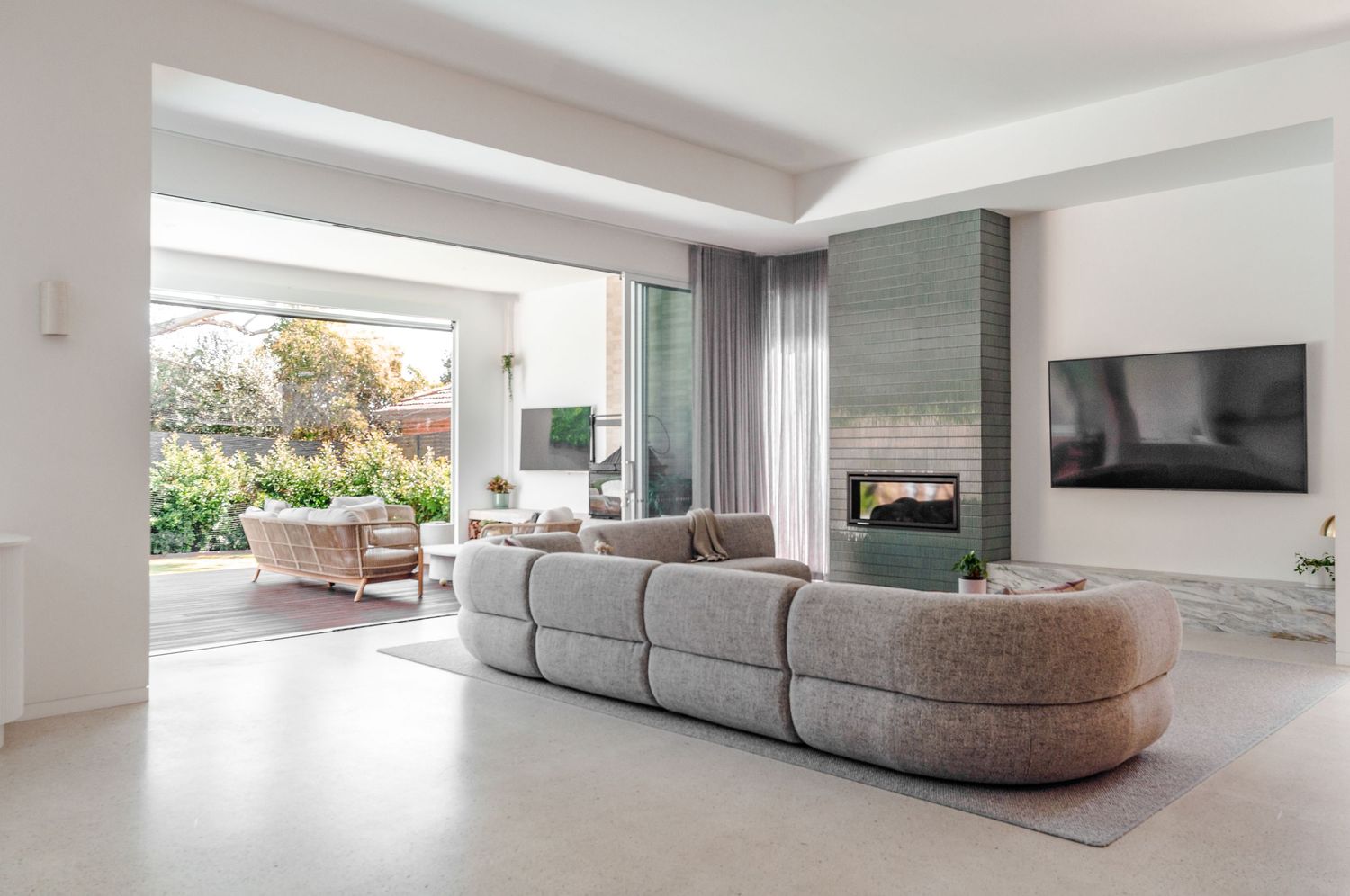 Modern minimalist living room with curved grey sectional sofa and bright white walls showcasing contemporary design.