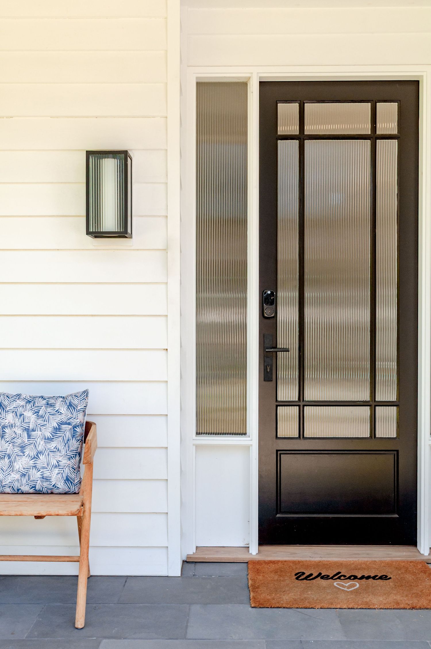 Contemporary black-framed front door design with geometric patterns on a white exterior wall.