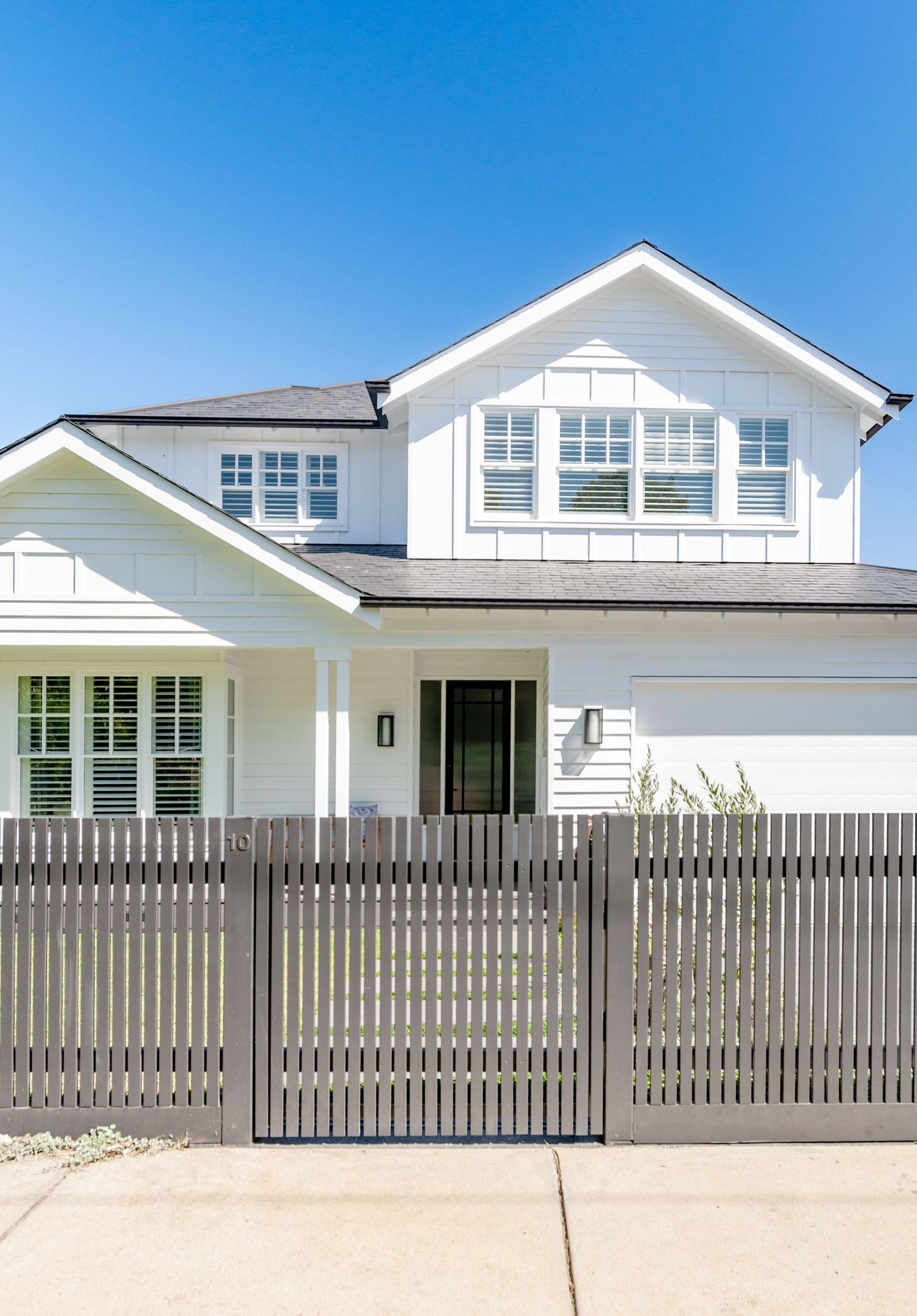 White modern house exterior with grey horizontal slatted fence and matching driveway gate.