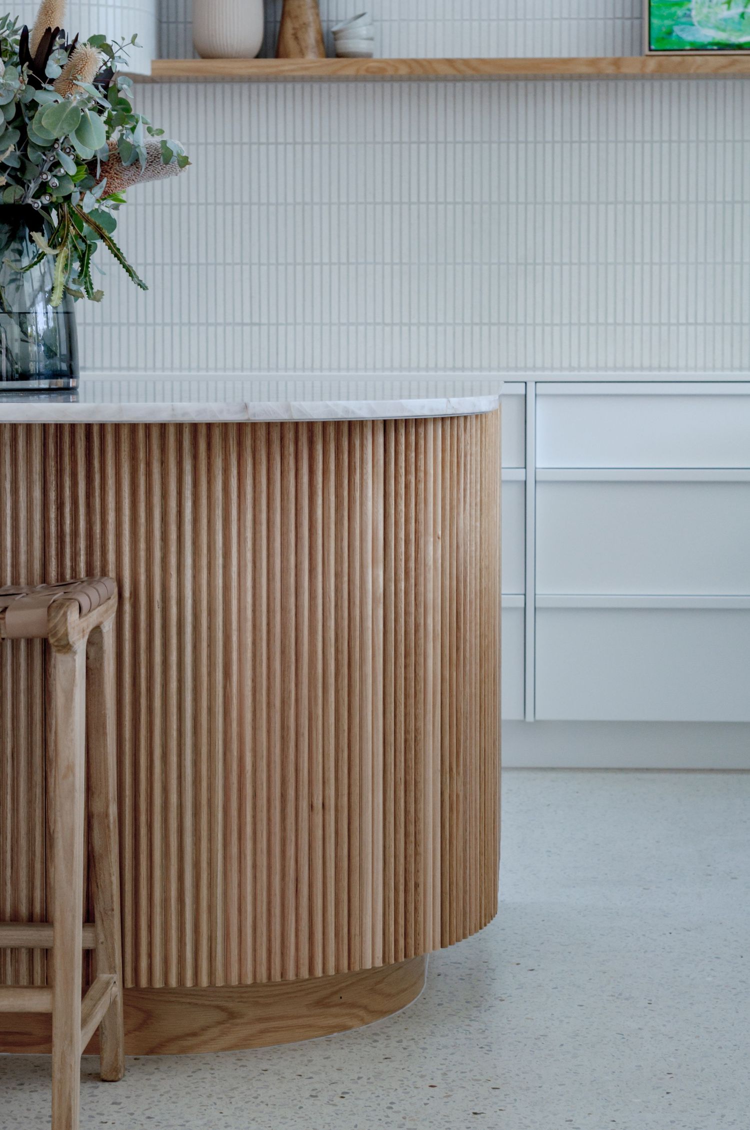 Modern wooden slat wall paneling curves elegantly around a corner, creating a sleek architectural detail in a minimalist space.