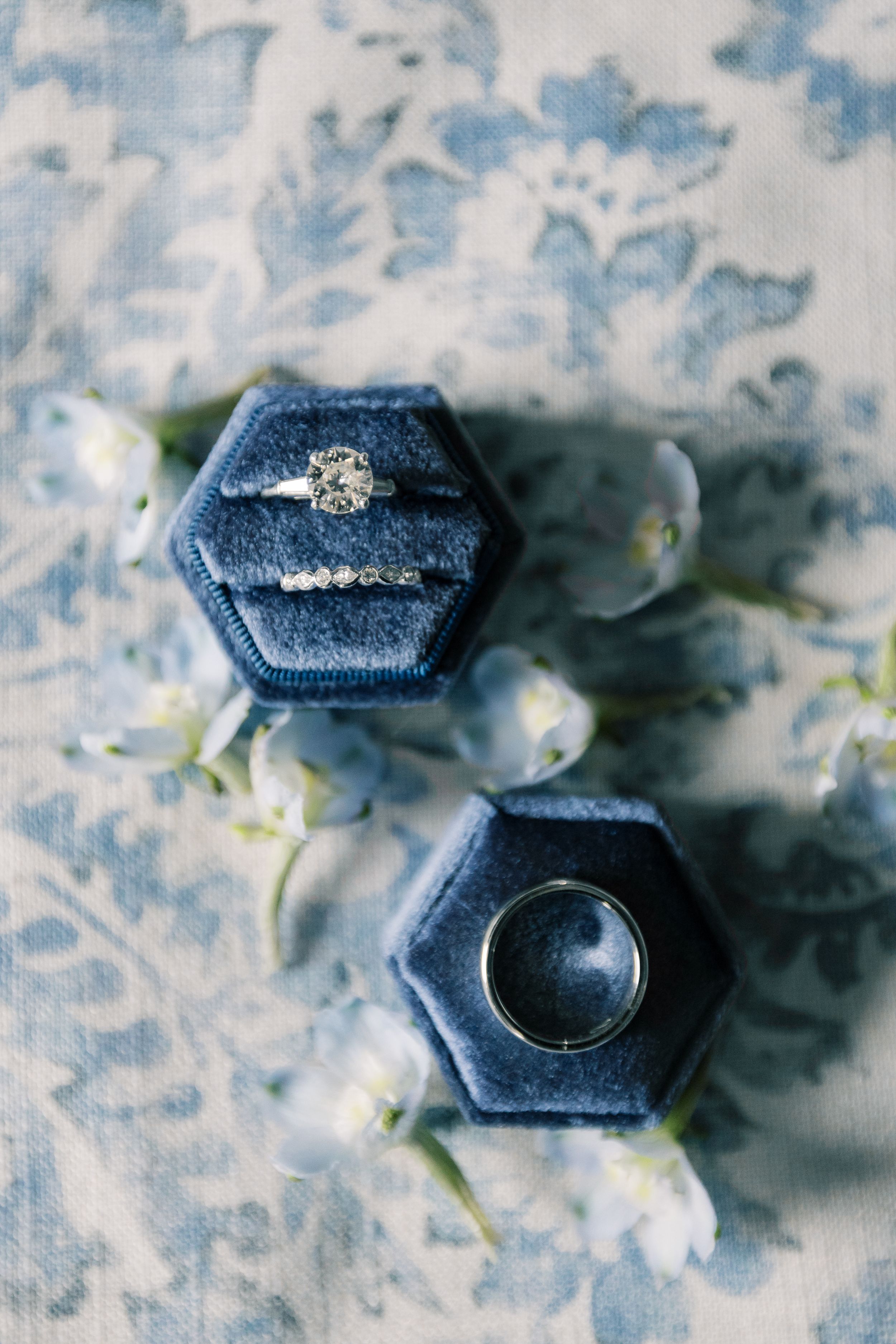 Close-up of dark blue velvet ring box with engagement ring sitting on delicate lace background.