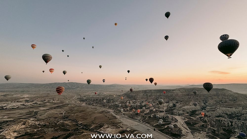 Dozens of hot air balloons filling the sky above Cappadocia's unique rock formations at dawn.