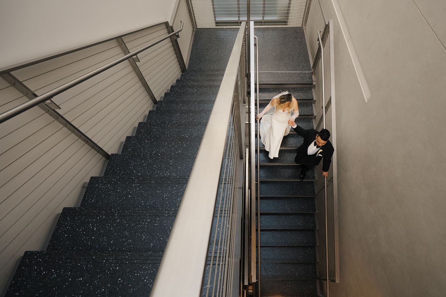 High angle view of two people sitting on carpeted stairs in a modern office building stairwell.
