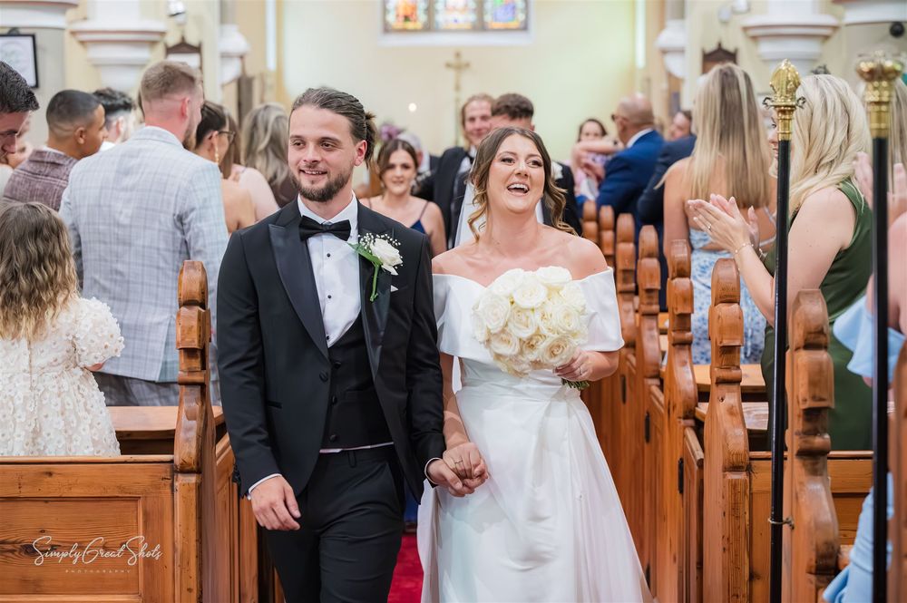 A joyful couple walks down the church aisle during their wedding ceremony with guests seated in wooden pews at St Peters Church in Cookley.