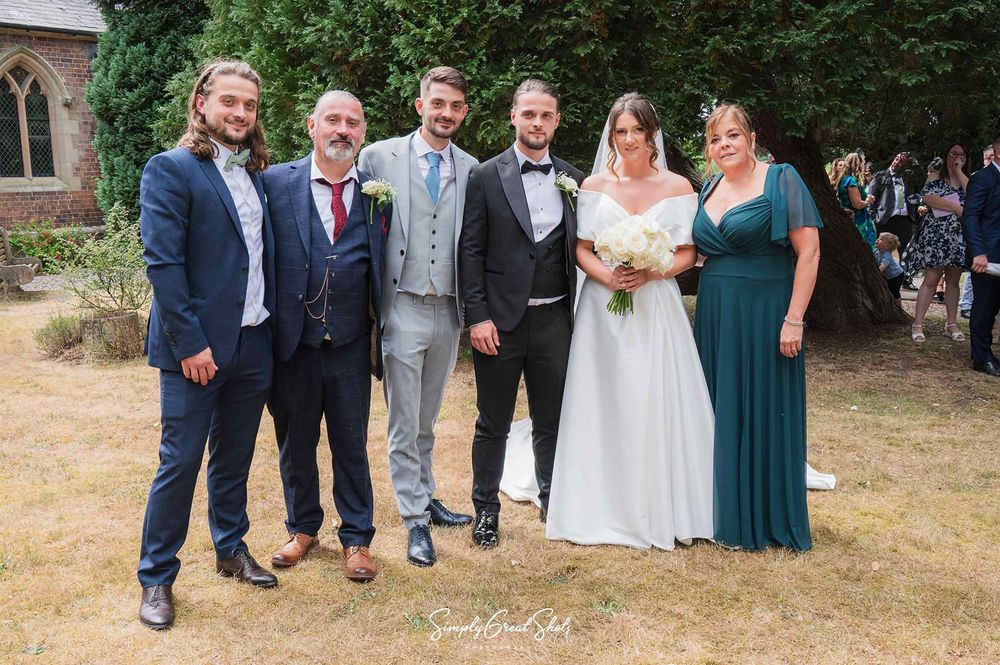 A Bride, Groom (just married) & the Groom's family outside St Peters Church in Kidderminster, posing for a family portrait.
