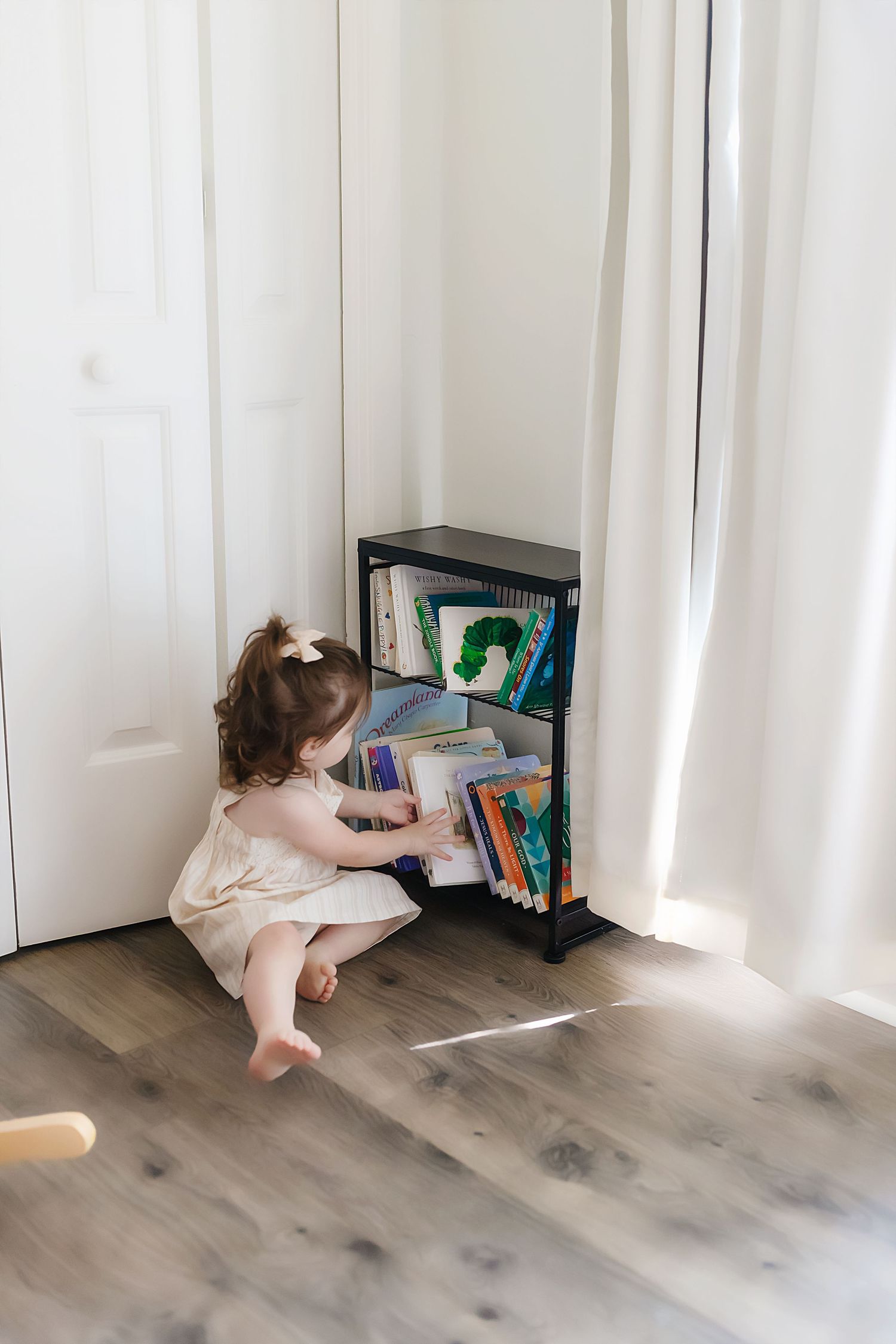 A series of photos showing someone crawling across a floor toward a small bookshelf in a bright room with white curtains.