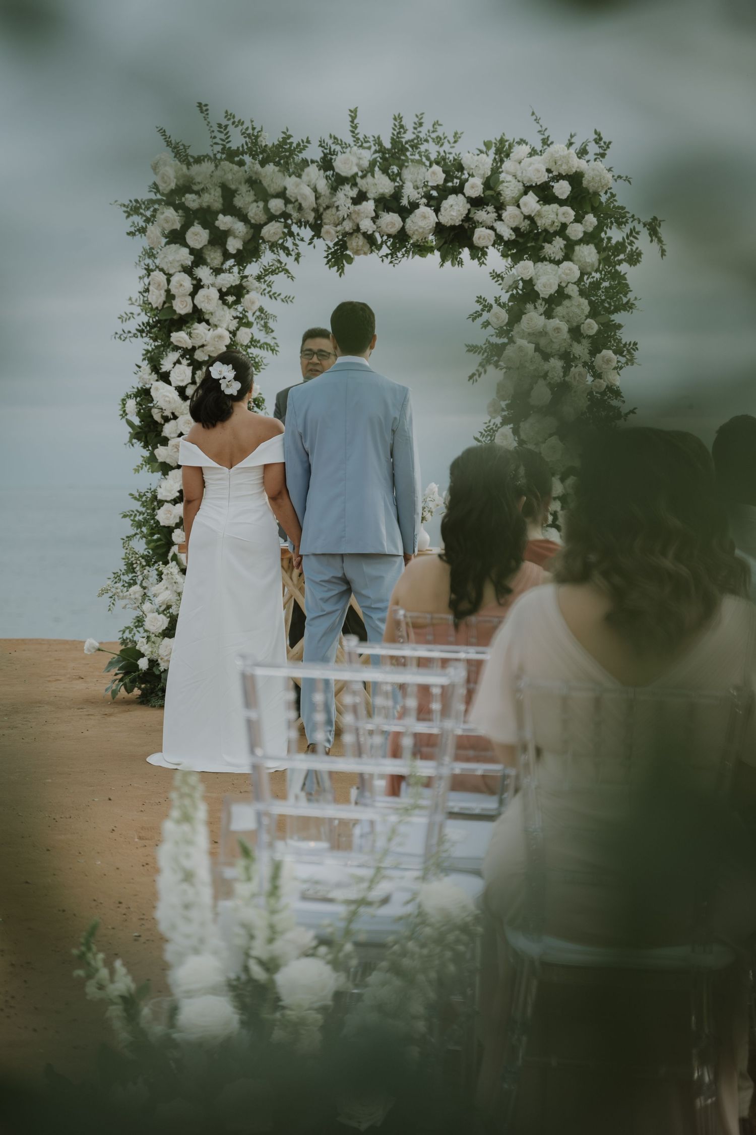 A romantic wedding ceremony with a stunning white floral arch and elegant chairs set against a dreamy backdrop.