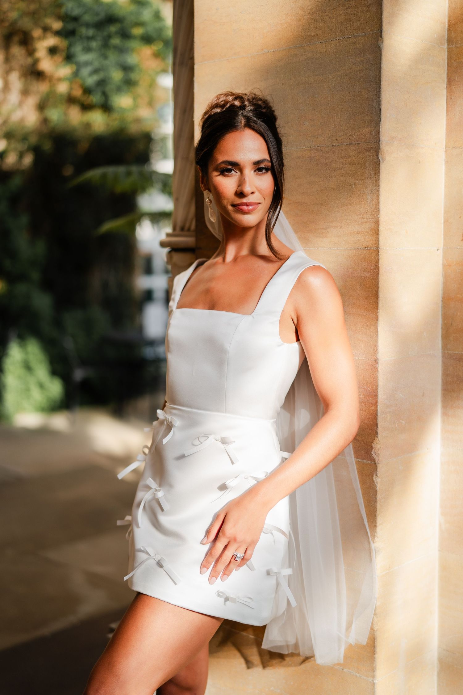 A white summer dress with bow details photographed against a classic architectural backdrop.