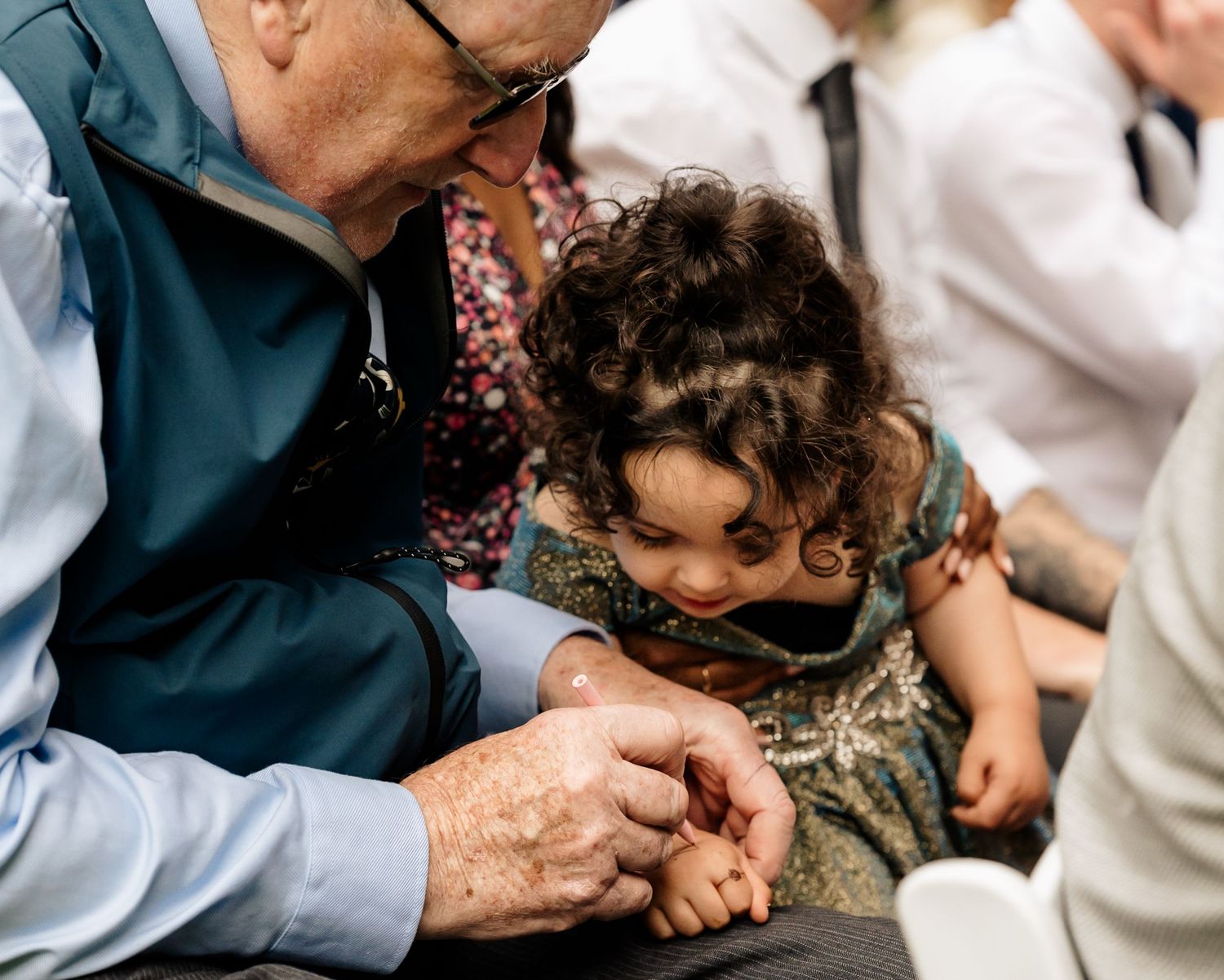 An elderly person and small child examine something together with focused attention and curiosity.