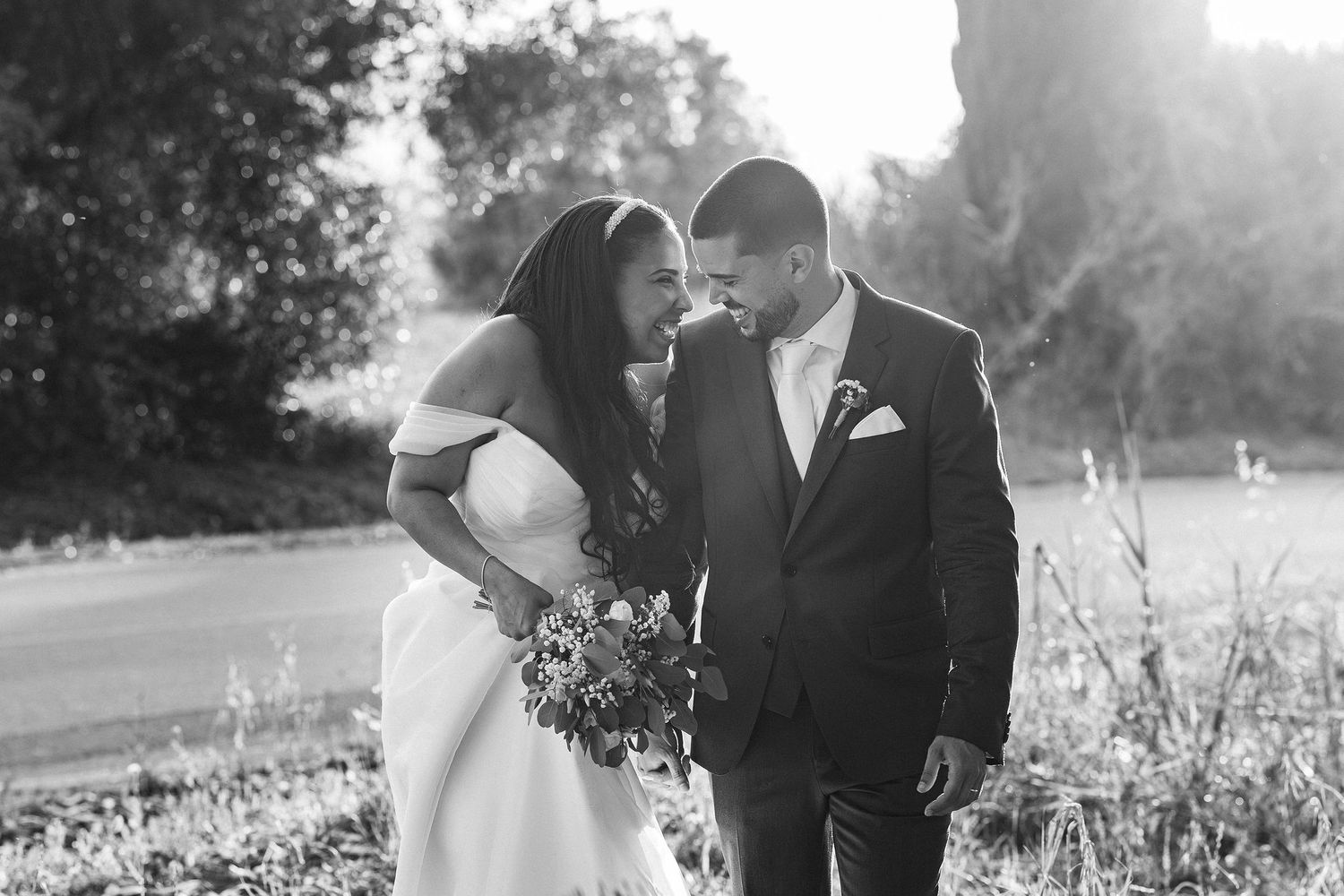 A loving couple shares an intimate moment together on their wedding day in a black and white outdoor setting.