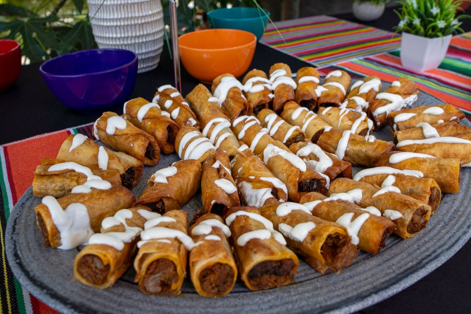Platter of freshly baked pastry rolls drizzled with white icing arranged in rows.